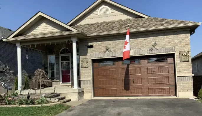 A residential home with a Canadian flag over a brown garage door.