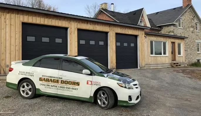 Peterborough Service Car in front of three installed black garage doors