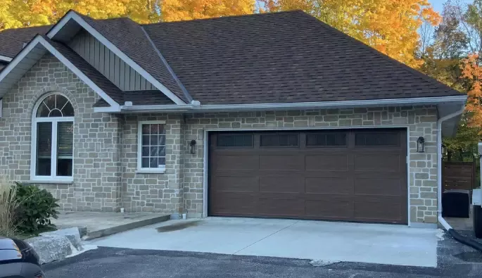 A brown garage door on a stone walled.