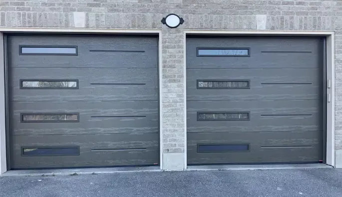Two gray garage doors featuring windows on the side, set against a neutral background.